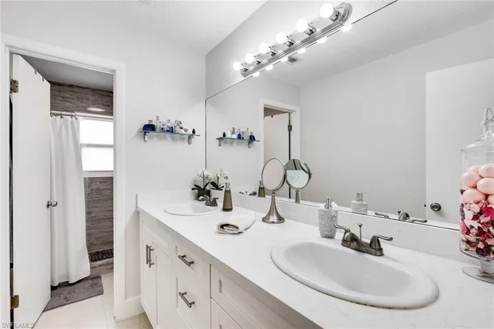 Bathroom with a sink, a shower with curtain, double vanity, and tile patterned flooring