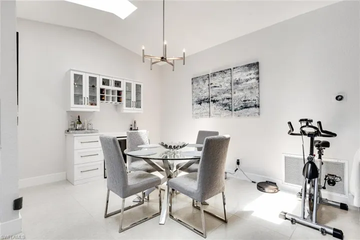 Dining room featuring a chandelier, baseboards, wet bar, and lofted ceiling