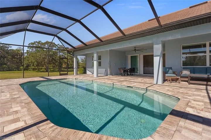 Outdoor pool featuring ceiling fan, a patio area, a sunroom, glass enclosure, and an outdoor hangout area