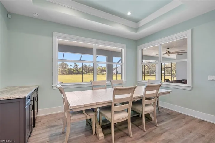 Dining room with a tray ceiling, light wood-style flooring, and ornamental molding