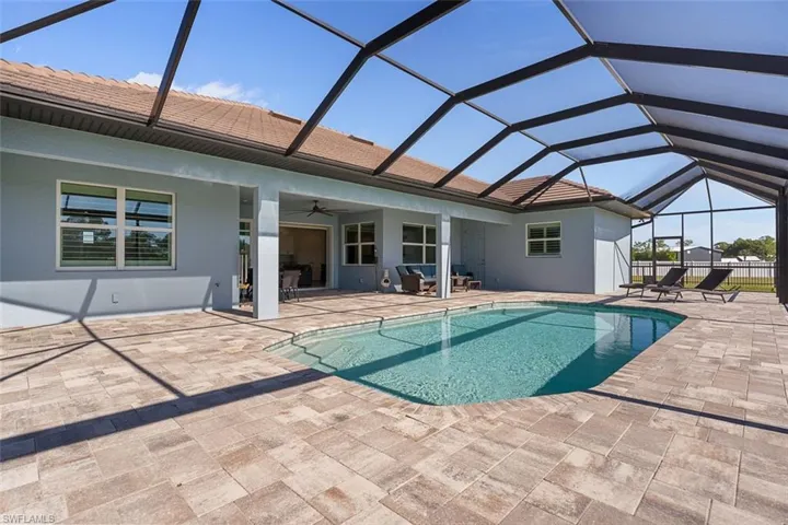 Outdoor pool with a sunroom, glass enclosure, a ceiling fan, and a patio area