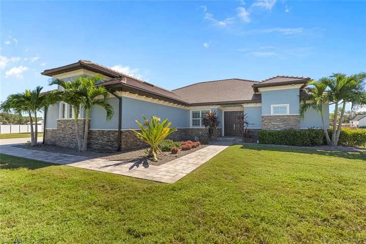 View of front of property featuring stone siding, stucco siding, a front yard, and a tile roof