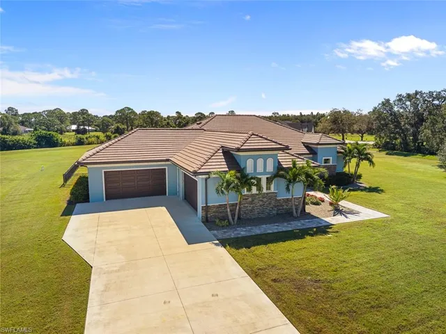 View of front of property with a front lawn, stone siding, stucco siding, and driveway