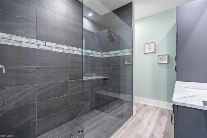 Full bath featuring vanity, light wood-style floors, and walk in shower