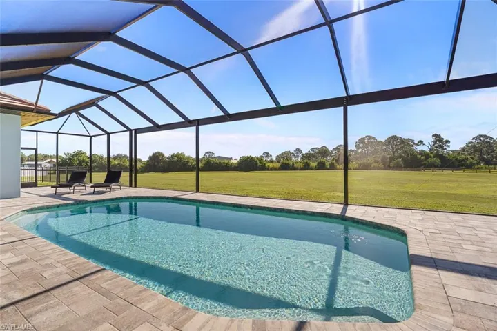 Swimming pool featuring a sunroom, glass enclosure, and a patio