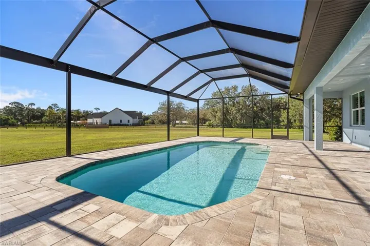 Swimming pool featuring a sunroom, a lawn, a patio, and a lanai