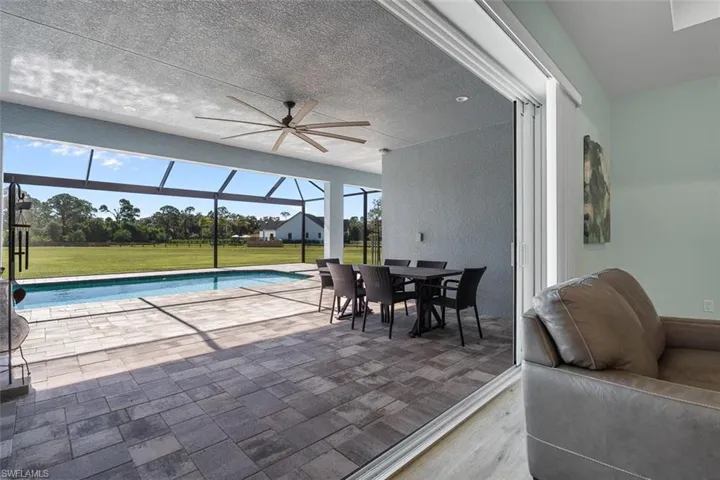 Swimming pool with a lawn, a patio area, glass enclosure, ceiling fan, and a sunroom