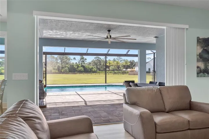 Living room featuring a sunroom, ceiling fan, wood finished floors, and plenty of natural light