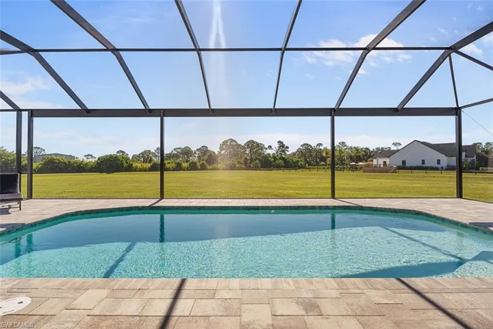 Outdoor pool featuring a lanai, a lawn, a sunroom, and a patio area
