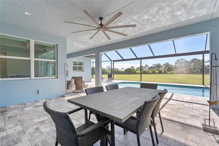 View of patio featuring a sunroom, a ceiling fan, an outdoor pool, glass enclosure, and outdoor dining space
