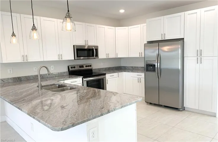 Kitchen with white cabinets, kitchen peninsula, stainless steel appliances, hanging light fixtures, and sink