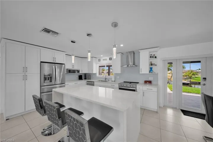 Kitchen with visible vents, a sink, wall chimney range hood, stainless steel appliances, and backsplash