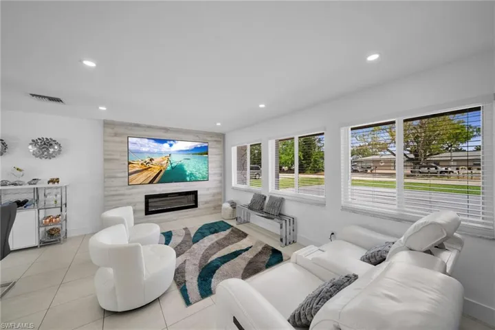 Living area with light tile patterned floors, a fireplace, visible vents, and recessed lighting
