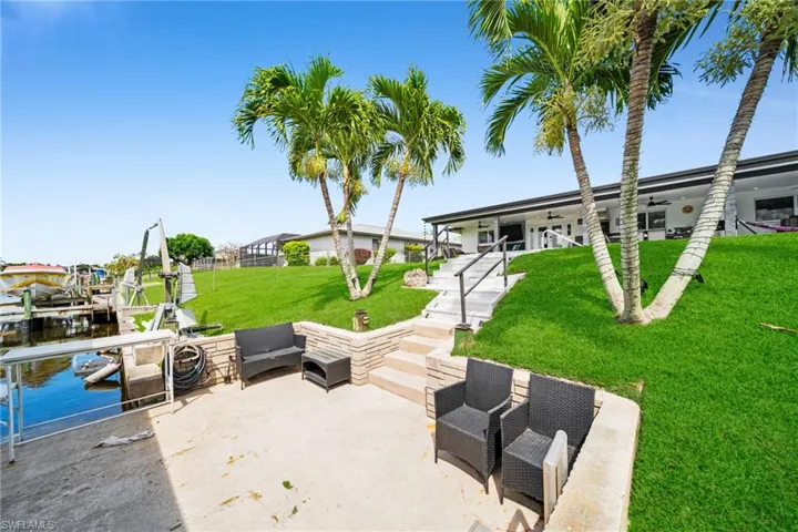 View of patio featuring a water view, outdoor lounge area, boat lift, and a dock
