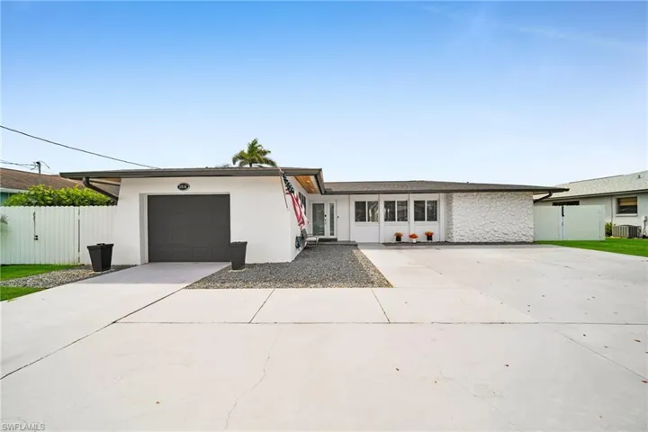 View of front of home with concrete driveway, a gate, central AC unit, a garage, and fence