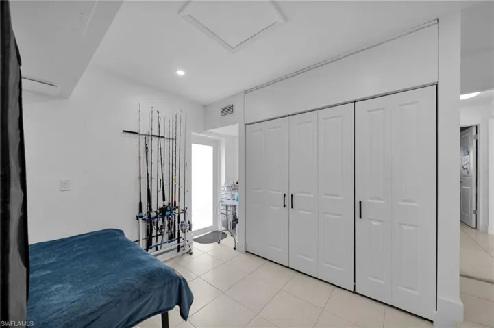 Bedroom with light tile patterned floors, visible vents, a closet, and attic access