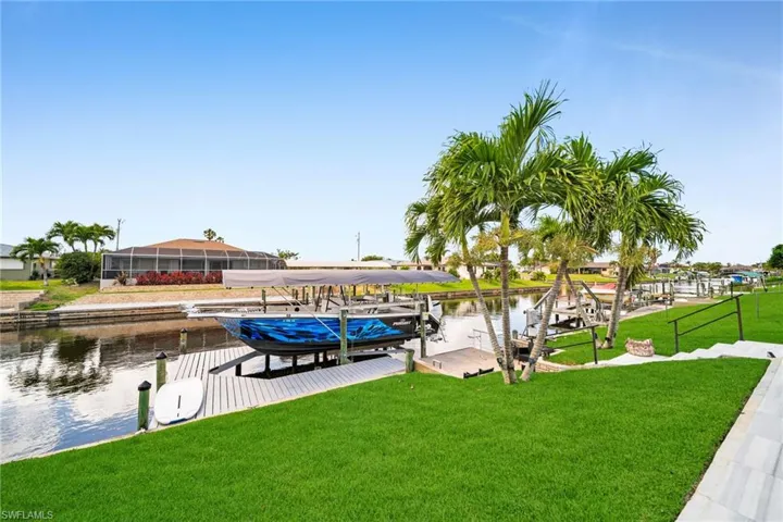View of dock with boat lift, a lawn, and a water view