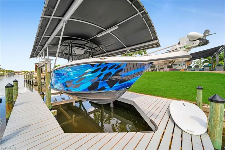 View of dock with boat lift, a yard, and a water view