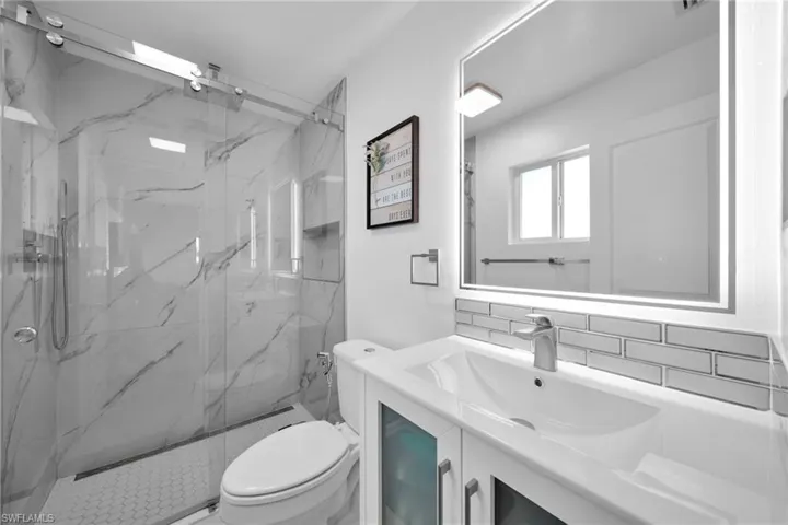 Full bath with toilet, a marble finish shower, backsplash, and vanity