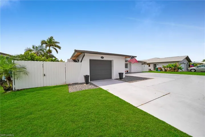 View of front of home featuring fence, a front lawn, a gate, an attached garage, and driveway