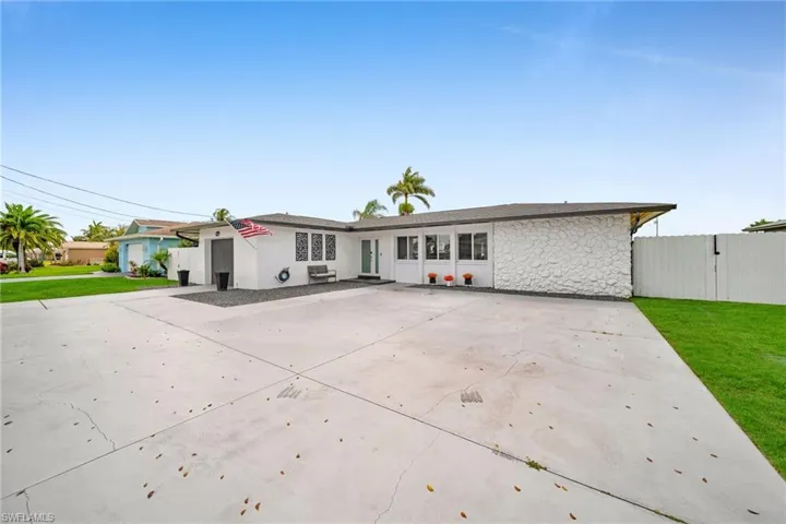 Single story home featuring driveway, stone siding, fence, and a front lawn