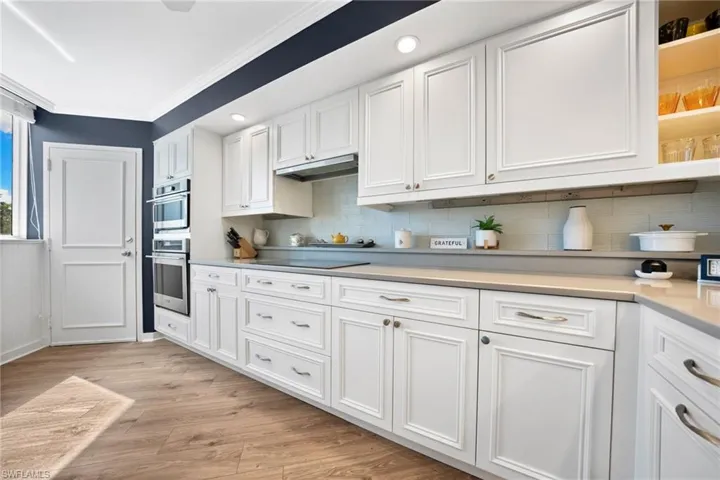 Renovated kitchen with white custom cabinetry & quartz counters, beautiful warm wood floors in the kitchen & living spaces