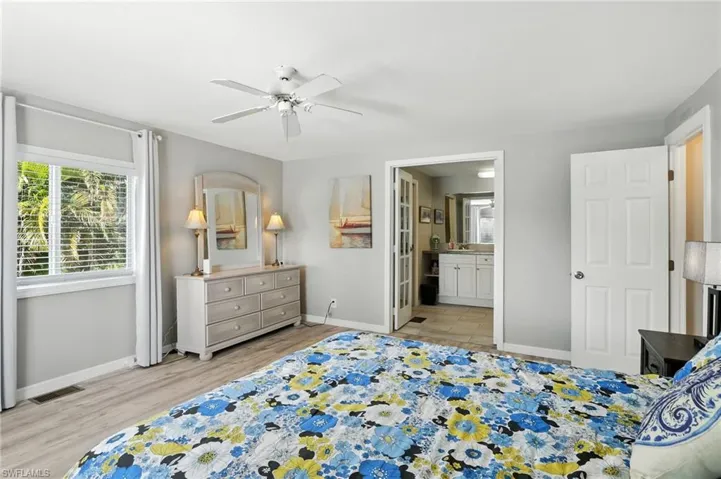 Bedroom with light wood finished floors, ensuite bath, and ceiling fan