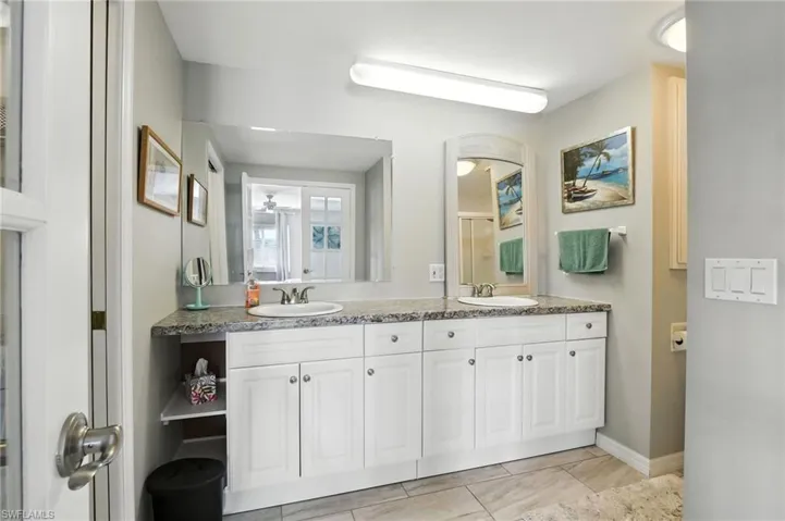 Full bathroom located in the Owners Suite featuring double vanity, tile patterned floors, and a shower with door