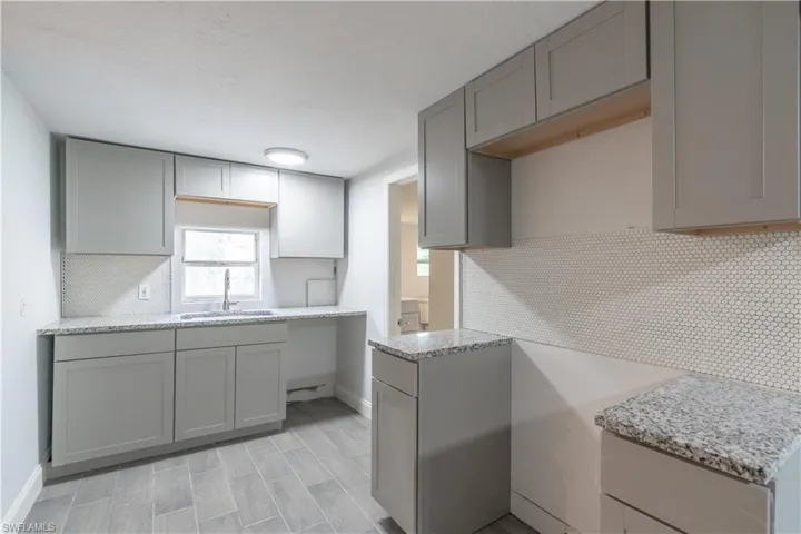 Kitchen featuring gray cabinets, sink, and tasteful backsplash
