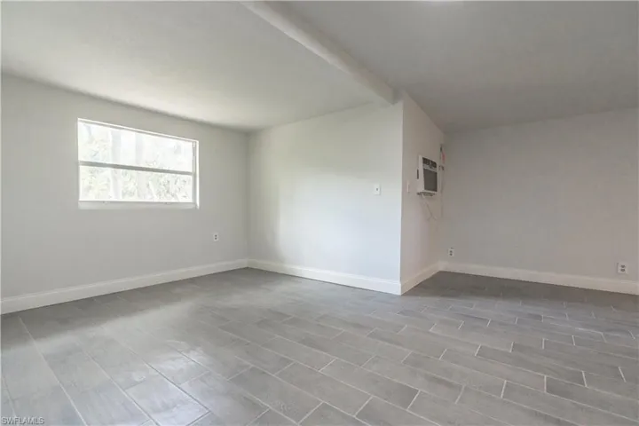 Unfurnished room featuring hardwood / wood-style flooring and a wall mounted air conditioner