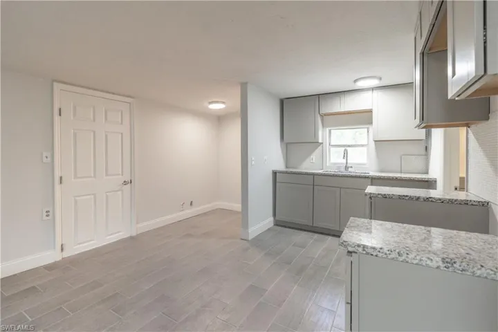 Kitchen featuring gray cabinets, light stone countertops, sink, and light hardwood / wood-style flooring