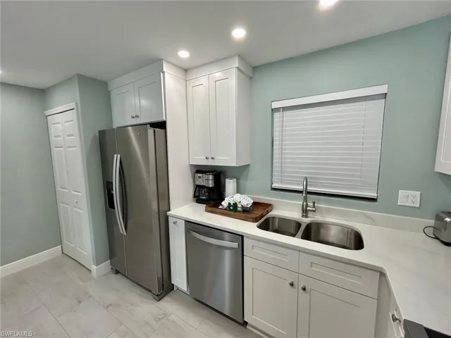 Kitchen featuring stainless steel appliances, white cabinets, light counters, recessed lighting, and light finish flooring