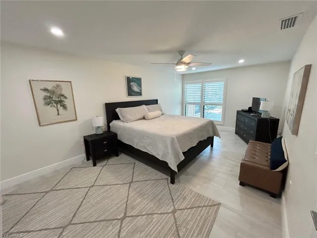 Primary bedroom with ceiling fan, recessed lighting, and light floors