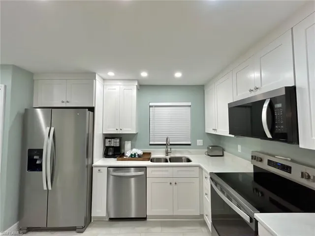 Kitchen with stainless steel appliances, white cabinetry, recessed lighting, and light countertops