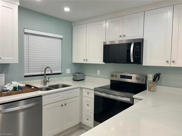 Kitchen featuring stainless steel appliances, white cabinets, light countertops, and recessed lighting