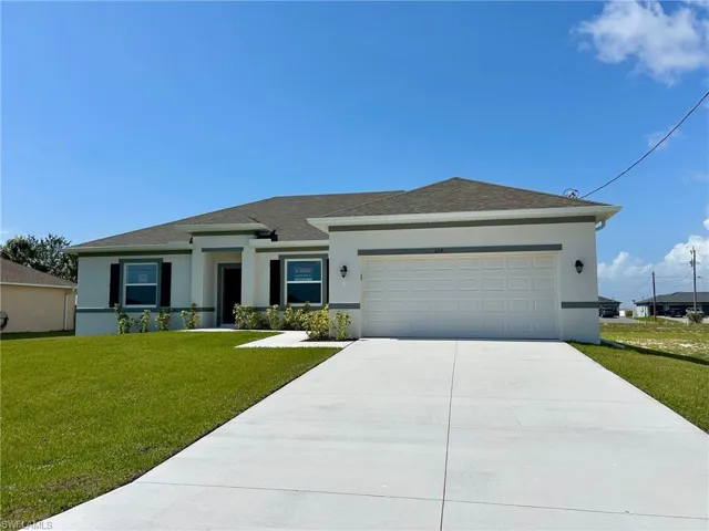 View of front facade featuring stucco siding, concrete driveway, an attached garage, and a front yard