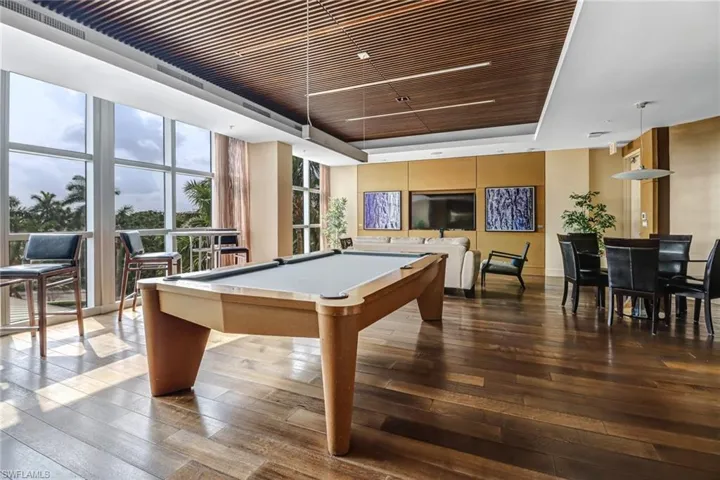 Recreation room with a tray ceiling, floor to ceiling windows, wood-type flooring, and billiards