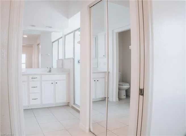 Bathroom with tile flooring, vanity with extensive cabinet space, an enclosed shower, and toilet
