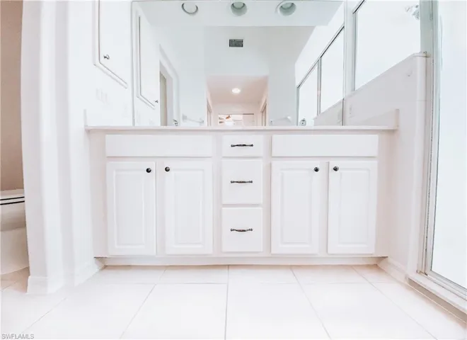 Bathroom featuring an enclosed shower, vanity, and tile floors