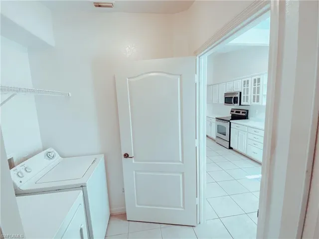 Laundry area with light tile flooring and washer and clothes dryer