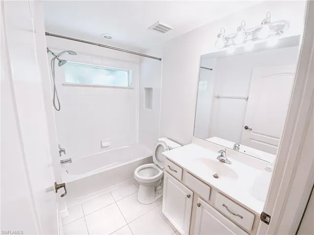 Full bathroom with vanity with extensive cabinet space, tile flooring, toilet, and tiled shower / bath combo