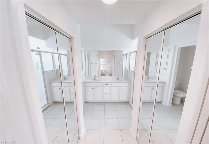 Bathroom featuring tile flooring, double vanity, and toilet
