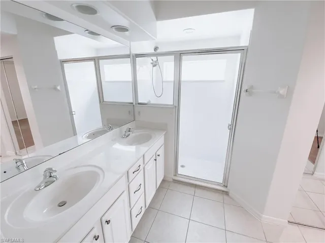 Bathroom featuring tile flooring, a shower with shower door, and double vanity