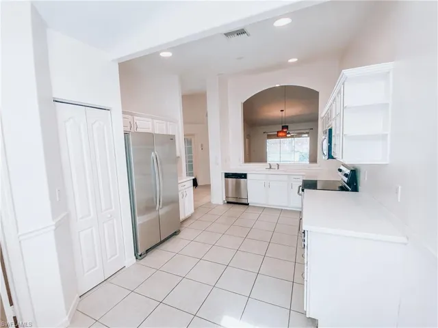 Kitchen featuring ceiling fan, appliances with stainless steel finishes, sink, light tile floors, and pendant lighting