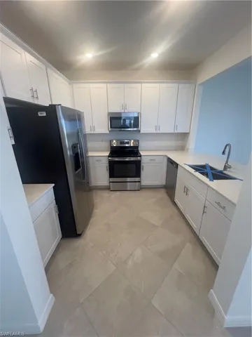 Kitchen featuring sink, white cabinetry, appliances with stainless steel finishes, and light tile patterned floors