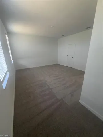 Unfurnished room featuring dark carpet