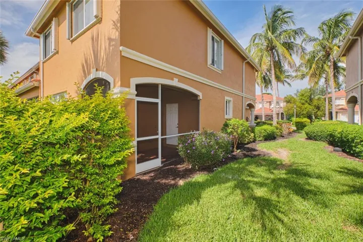 Rear view of property featuring stucco siding, a sunroom, and a lawn