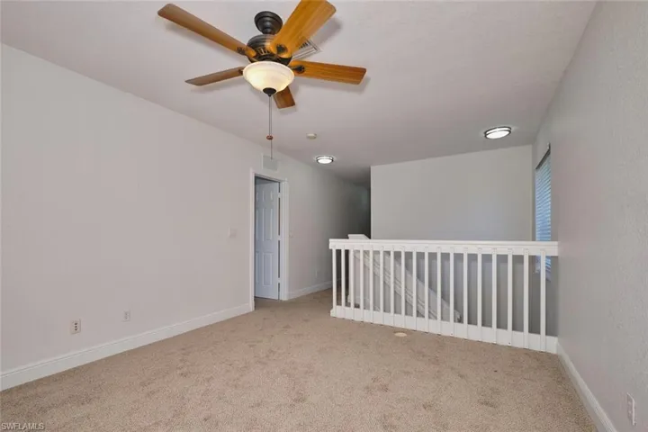 Carpeted spare room featuring baseboards and ceiling fan