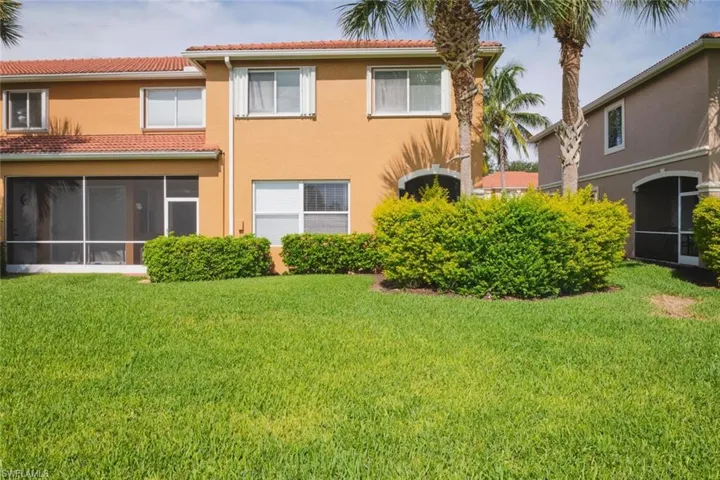 Back of property with a sunroom, stucco siding, a lawn, and a tiled roof