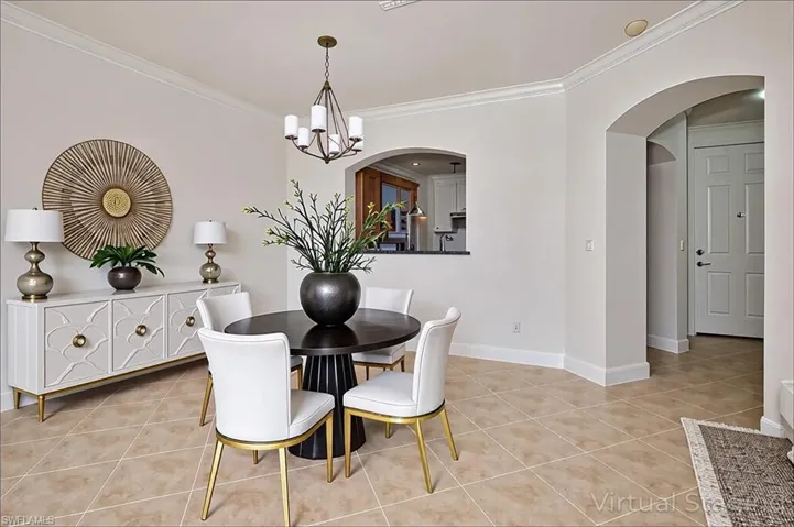 Dining space with arched walkways, ornamental molding, light tile patterned floors, and a chandelier - virtually staged